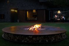 a fire pit sitting on top of a lush green field next to a house at night