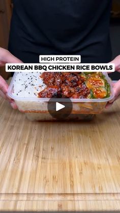 a person holding up a container with chicken rice bowls in it on a wooden table