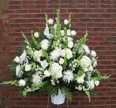 a bouquet of white flowers sitting on top of a table next to a brick wall