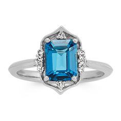 A single emerald cut London blue topaz gemstone (approx. 1.91 carat TW) is beautifully highlighted by eight round diamonds (approx. .10 carat TW) in this vintage style ring. Crafted from quality 14 karat white gold  the 2mm wide rings band features a unique design and has a total gem weight of approximately 2.01 carats. Topaz Diamond Ring, Topaz And Diamond Ring, December Birthstone Jewelry, Shop Rings, Rings And Bracelets, Vintage Style Rings, Let It Shine, Blue Topaz Gemstone, White Gold Chains