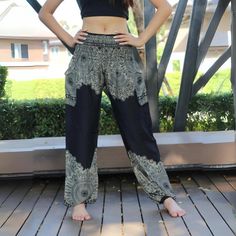 a woman standing on top of a wooden floor wearing black and white pants with paisley print