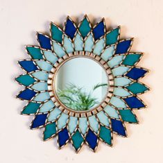 a mirror with blue and white glass in the shape of a flower on a wall