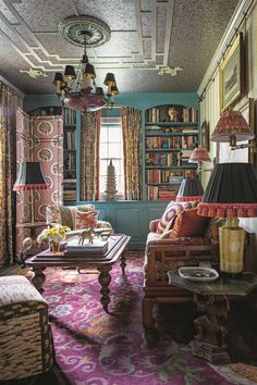 a living room filled with lots of furniture and bookshelves covered in colorful curtains