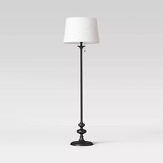 a black floor lamp with a white shade on the top and bottom part of it