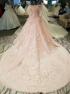 a wedding dress is on display in a room with other gowns and dresses behind it