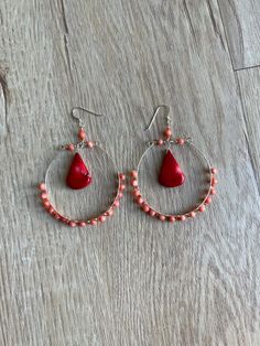 2 3/4" long earrings featuring natural light pale orange coral and red coral briolettes/drops.  The total length of these earrings is 2 3/4". The width of the actual hoops is 2".  The hoops are made of stainless steel memory wire with hand wire wrapped coral beads coiled around it. The coral beads are pale orange, smooth, round and measure 4mm. In between each 4mm bead is a small coral bead in a slightly darker shade. Those are smooth, round and measure 1.5mm.  There are large red coral briolett Red Dangle Hoop Earrings Nickel Free, Coral Jewelry With Dangling Beads For Gift, Red Teardrop Hoop Earrings With Ear Wire, Orange Small Hoop Earrings With Ear Wire, Red Teardrop Chandelier Earrings With Ear Wire, Handmade Coral Dangle Jewelry, Handmade Adjustable Red Teardrop Earrings, Adjustable Handmade Red Teardrop Earrings, Adjustable Red Hoop Earrings With Dangling Beads