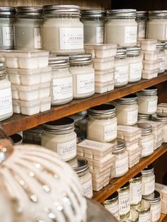 shelves filled with jars and candles on top of wooden shelves next to eachother