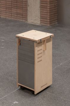 a wooden box sitting on top of a cement floor next to a brick wall and building