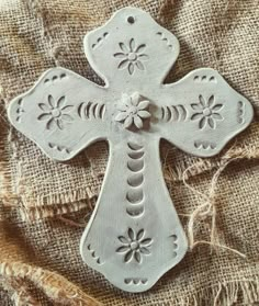 a white ceramic cross sitting on top of a piece of cloth