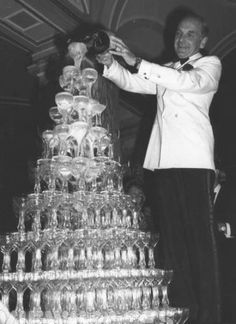 a man standing next to a large stack of wine glasses on top of a table