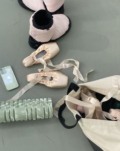 several ballet shoes are laying on the floor next to a cell phone and a bag