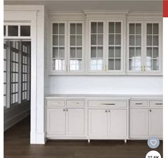 an empty kitchen with white cabinets and wood floors