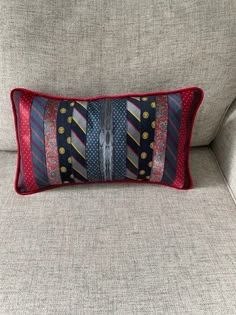 a decorative pillow on the back of a couch with red and blue trimmings