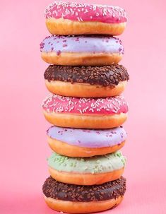 a stack of doughnuts with sprinkles on them against a pink background