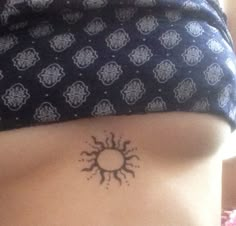 a woman's stomach with a small sun tattoo on it