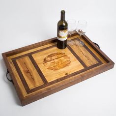 a wine bottle and two glasses on a wooden tray