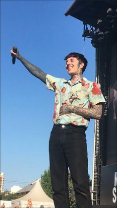 a man standing on top of a stage with his arms out in front of him