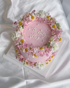 a pink cake decorated with flowers and the words happy birthday on it's side