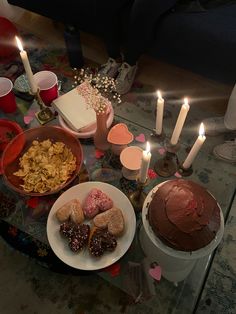 a table topped with lots of different types of food and candles on top of it