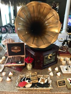 an old - fashioned record player is surrounded by desserts and candies on a table