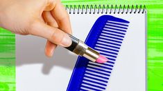 a person holding a pen and writing on a piece of paper next to a blue comb