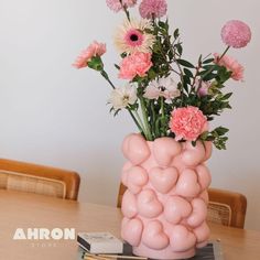 a vase filled with pink and white flowers on top of a wooden table next to a book