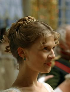 a woman in a white dress with braids on her head looking off to the side