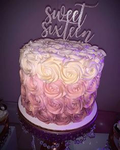 a pink and white cake with the word sweet sixteen on top is sitting on a table