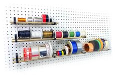 several spools of thread are hanging on the wall behind two pegs that hold different colored ribbons