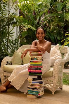 a woman sitting on a couch with a stack of books in front of her