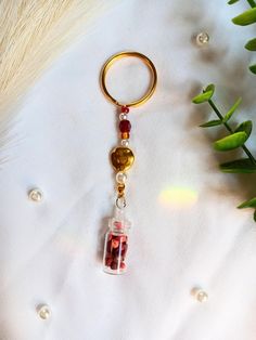 a keychain with a glass bottle filled with red liquid on top of a white surface