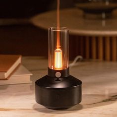 a table with a lamp on top of it and a book in the back ground