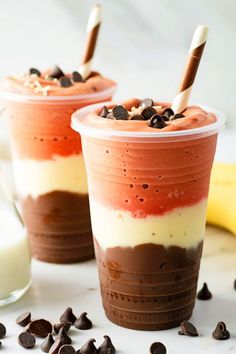 two dessert cups with chocolate chips, cream and milk on the side next to a banana