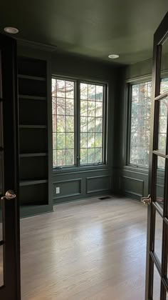 an empty room with wood floors and green walls