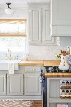 a kitchen with white cabinets and wooden counter tops