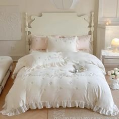 a large white bed sitting in a bedroom next to a night stand with flowers on it