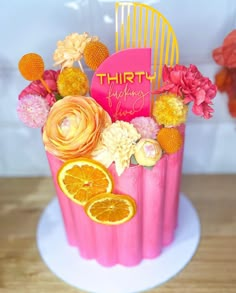 a pink cupcake decorated with oranges and flowers