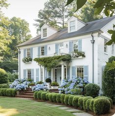 a large white house with blue shutters and flowers