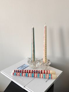 two candles sitting on top of a white table