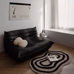 a black leather futon in front of a window with a clock on the wall