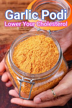 a person holding a jar filled with powdered orange colored liquid and the words garlic podi lower your cholesterol