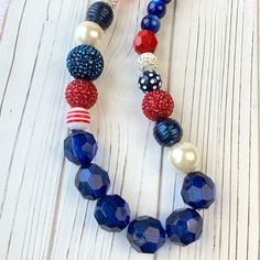 Here's a real firecracker of a necklace that's ready to celebrate 4th of July with you! Our Lenora Dame signature Queen Mum style large beaded necklace in patriotic red, white and blue beads. A harmonious mix of beads from cat's eye, pearl, rhinestone pave, big red and blue bumpy pave, navy with glitter and oversized navy faceted Lucite. The perfect necklace to accessorize for a July 4th BBQ, Memorial Day, Military ceremonies, and other military occasions. The necklace measures 18.5-Inches with Festive Blue Necklaces With Large Beads, Festive Blue Necklace With Large Beads, Patriotic Red Jewelry For Party, Red Patriotic Jewelry For Party, Adjustable Blue Jewelry For 4th Of July, Patriotic Blue Jewelry With Colorful Beads, Adjustable Patriotic Red Necklace, Blue Jewelry For 4th Of July Party, Blue Jewelry For Independence Day Gift