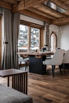 the dining room table is surrounded by white chairs and wooden beams, along with large windows that look out onto snow covered mountains