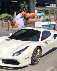 the man is hanging upside down on the white sports car