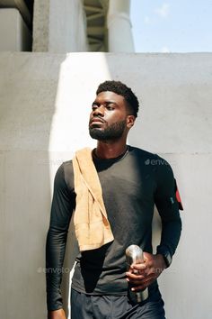 a man with a towel on his shoulder is standing in front of a white wall