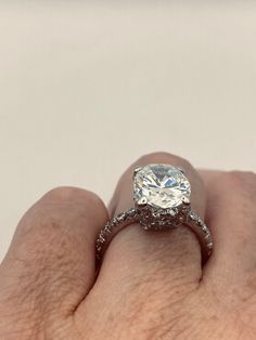 a close up of a person's hand holding a ring with a diamond in it