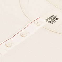 Short-sleeve henley.
Made of 180 g/㎡ organic cotton 1x1 rib jersey.
Adjusted fit.
Cotton button tape and red overstitch.
100% "GOTS" certifed organic cotton.
Quality garments made in Portugal. White Cotton T-shirt With Henley Neckline, White Cotton Henley With Buttons, Classic Cotton Henley, Classic Cotton Henley With Buttons, White Henley Neckline Cotton T-shirt, White Cotton Henley Neckline T-shirt, Cotton Henley T-shirt With Buttons, Cotton Henley For Everyday Wear, Cotton Henley Neckline T-shirt With Buttons