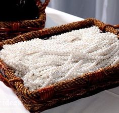 two wicker baskets filled with beads on top of a white table cloth covered table