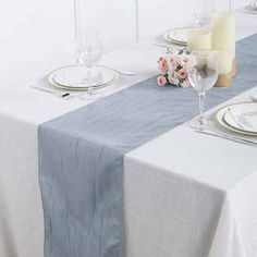 the table is set with white and blue linens, silverware, and candles