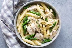 a bowl filled with pasta, chicken and asparagus on top of a table